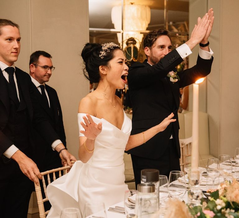 Bride and groom cheering during wedding breakfast