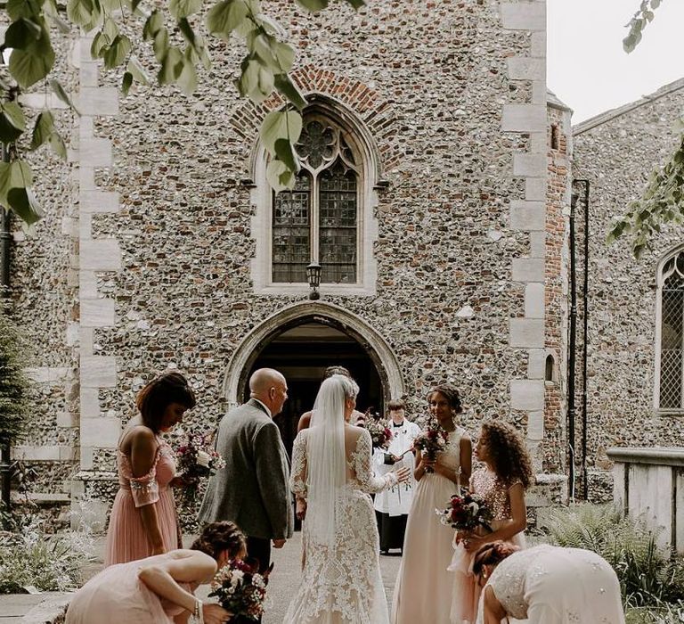 Bride in Lillian West wedding dress outside the church