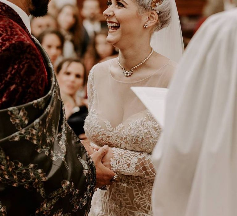 Bride with short hair and bridal crown laughing during the wedding ceremony