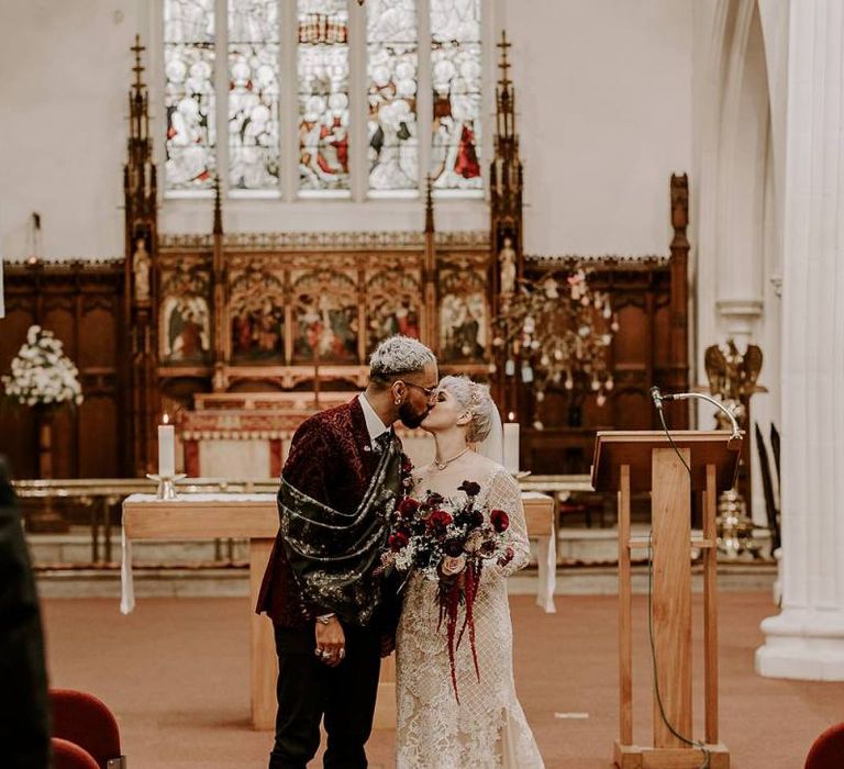 Stylish bride and groom kissing during the wedding ceremony