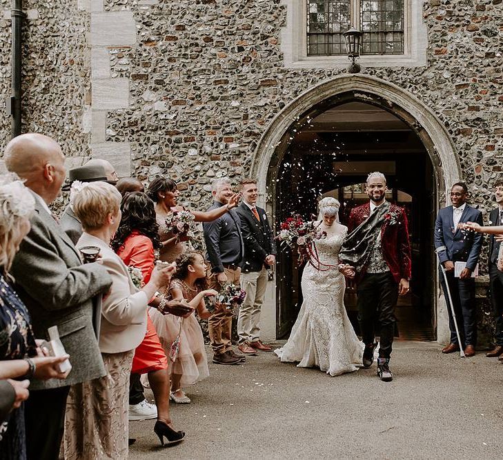 Bride and groom confetti exit with bride in lace Lillian West wedding dress