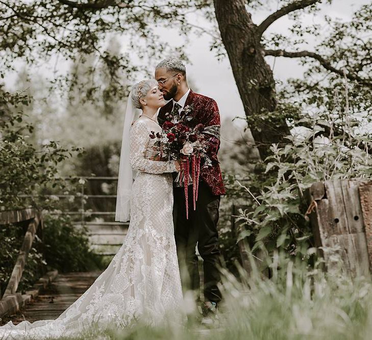 Groom in a velvet blazer kissing his bride in a lace Lillian West wedding dress