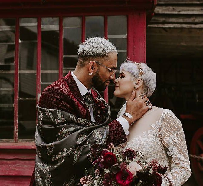 Stylish groom in red blazer and silk shawl kissing his bride