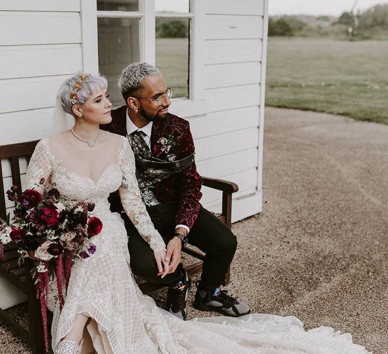 Stylish bride and groom sitting on a bench together with bride in Lillian West wedding dress