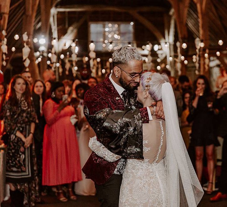 Bride and groom first dance in a festoon lit barn with bride in Lillian West wedding dress