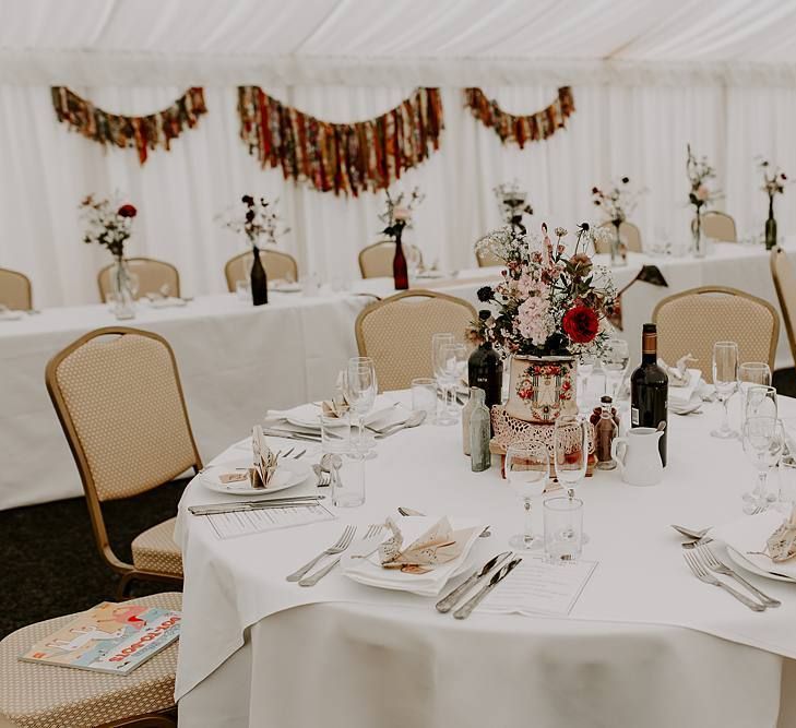 DIY table centrepiece with stacked books, doilies and wild flowers in vintage tin