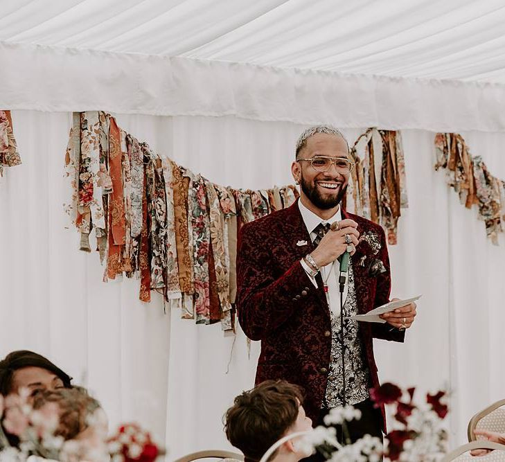 Groom giving a wedding speech with fabric bunting backdrop