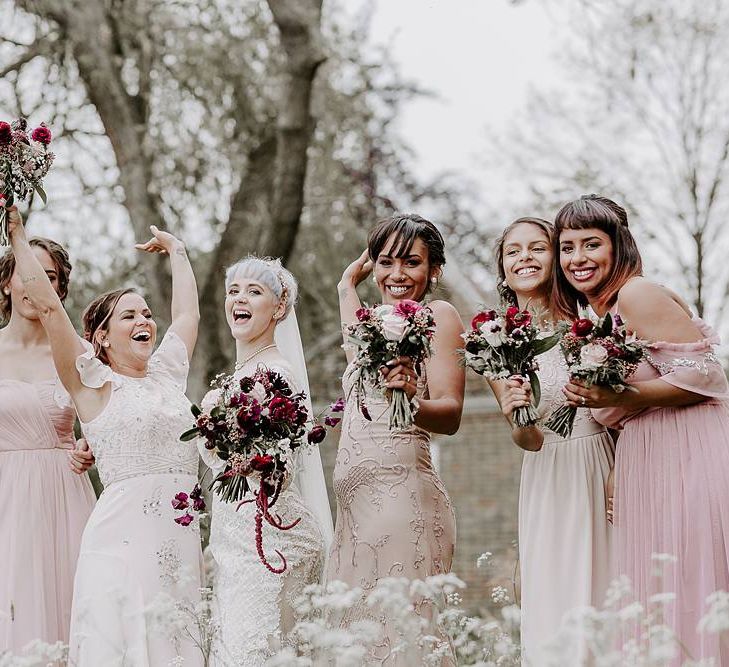 Fun bridal party portrait with bridesmaids in pink dresses and bride in Lillian West dress