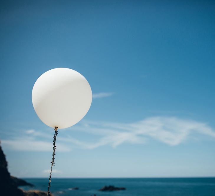 Oversized White Balloon with Foliage Trail | Gypsophila Arch and Giant Balloons for an Outdoor Coastal Wedding | Toby Lowe Photography