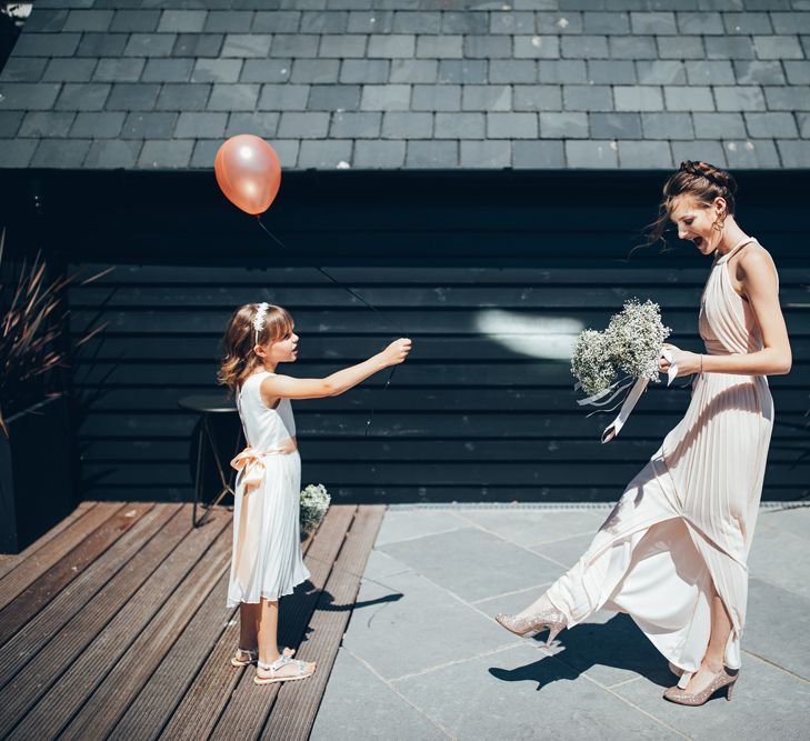 Bridesmaid in Soft Pink ASOS Halterneck Dress | Gypsophila Bouquets Tied with Pink Trailing Ribbon | Sequined Pink Shoes | Flower Girl in White Dress with Pink Sash | Pink Balloon with Black String | Gypsophila Arch and Giant Balloons for an Outdoor Coastal Wedding | Toby Lowe Photography