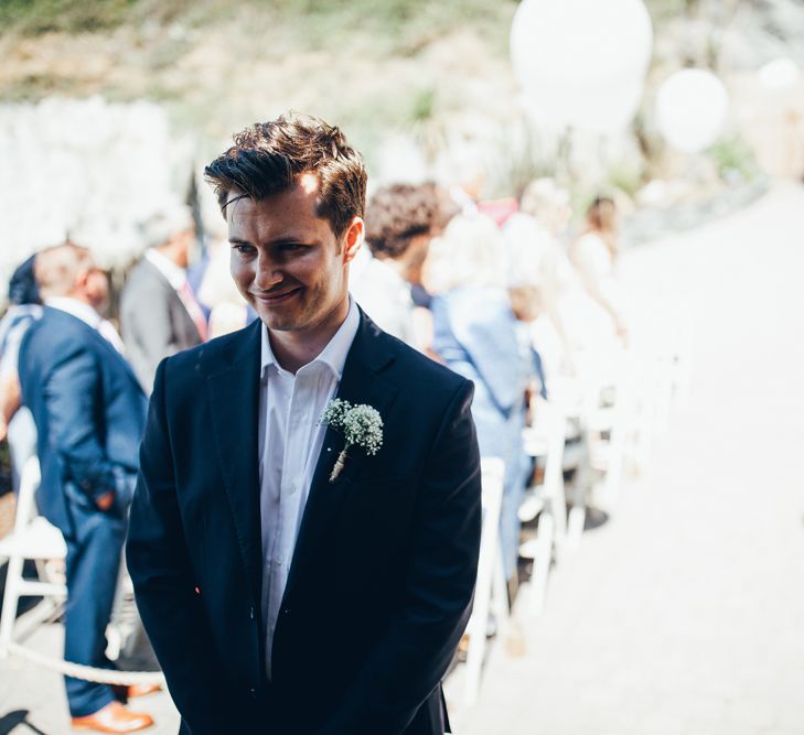 Groom in Navy Blue Suit | Gypsophila Buttonhole | Groom Waiting at Altar | Gypsophila Arch and Giant Balloons for an Outdoor Coastal Wedding | Toby Lowe Photography