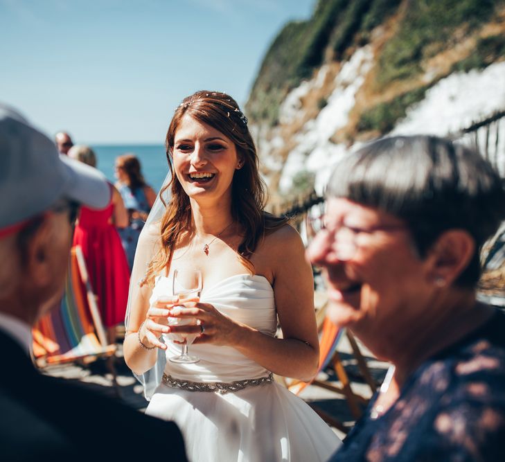 Bride in Strapless Ballgown Dress by Pronovias with Crystal Belt | Wedding Reception Drinks at Tunnels Beaches in Devon | Gypsophila Arch and Giant Balloons for an Outdoor Coastal Wedding | Toby Lowe Photography