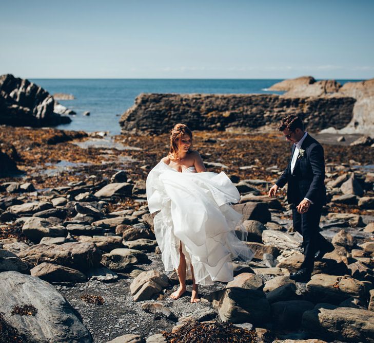 Bride in Strapless Ballgown Dress by Pronovias with Crystal Belt | Groom in Navy Suit with Gypsophila Buttonhole | Gypsophila Arch and Giant Balloons for an Outdoor Coastal Wedding | Toby Lowe Photography