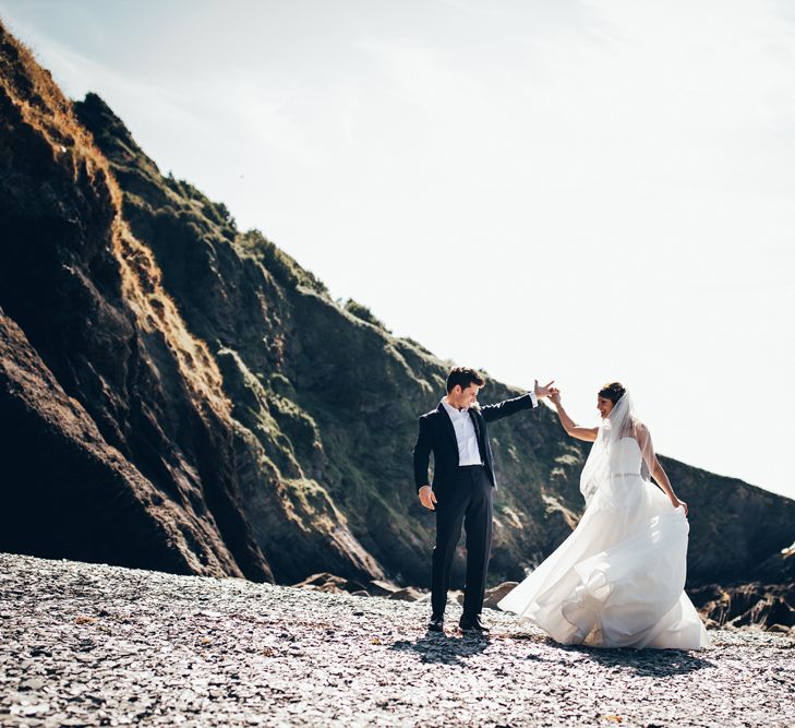 Bride in Strapless Ballgown Dress by Pronovias with Crystal Belt | Fingertip Veil | Groom in Navy Suit with Gypsophila Buttonhole | Gypsophila Arch and Giant Balloons for an Outdoor Coastal Wedding | Toby Lowe Photography