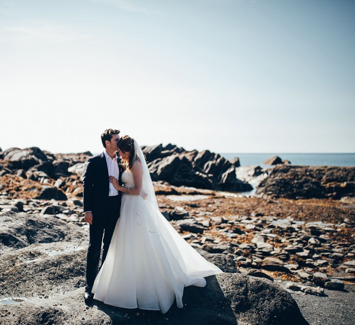 Bride in Strapless Ballgown Dress by Pronovias with Crystal Belt | Fingertip Veil | Groom in Navy Suit with Gypsophila Buttonhole | Gypsophila Arch and Giant Balloons for an Outdoor Coastal Wedding | Toby Lowe Photography