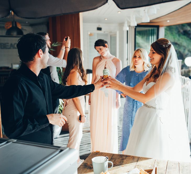 Bride in Strapless Ballgown Dress by Pronovias with Crystal Belt | Fingertip Veil | Bridesmaid in Soft Pink ASOS Halterneck Dress | Ice Cream Cart | Gypsophila Arch and Giant Balloons for an Outdoor Coastal Wedding | Toby Lowe Photography