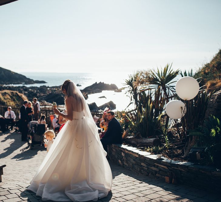 Bride in Strapless Ballgown Dress by Pronovias with Crystal Belt | Fingertip Veil | Ice Cream | Gypsophila Arch and Giant Balloons for an Outdoor Coastal Wedding | Toby Lowe Photography