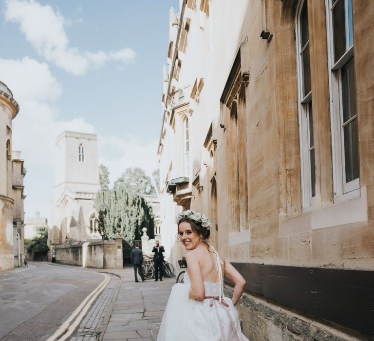 Bride walking through Oxford for her wedding wearing lace dress and flower crown