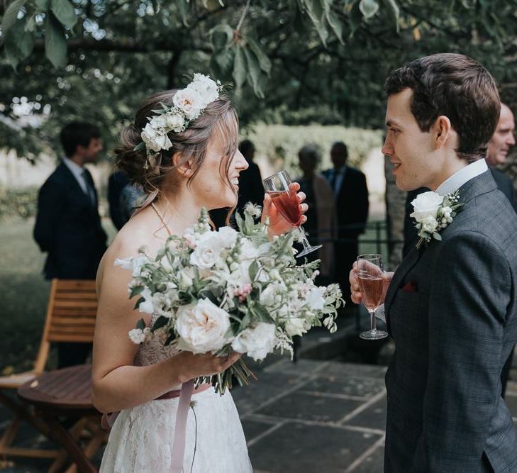 Bride and groom tie the knot at intimate celebration with a white floral bouquet and a flower head crown