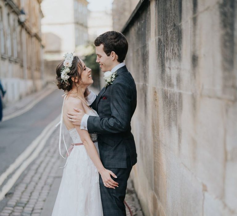 Bride and groom tie the knot at intimate celebration with a white floral bouquet and a flower head crown