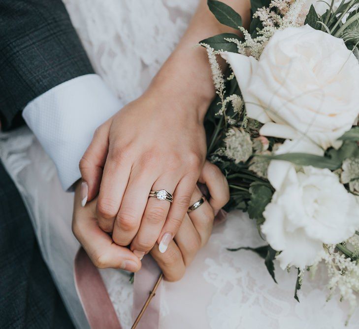 White flower bouquet details and wedding bands at intimate celebration with a beautifully laced dress