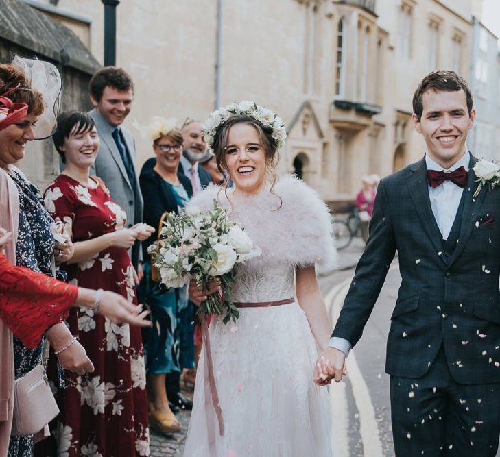 Bride and groom confetti shot at an intimate celebration with a bridal shrug and a flower head crown