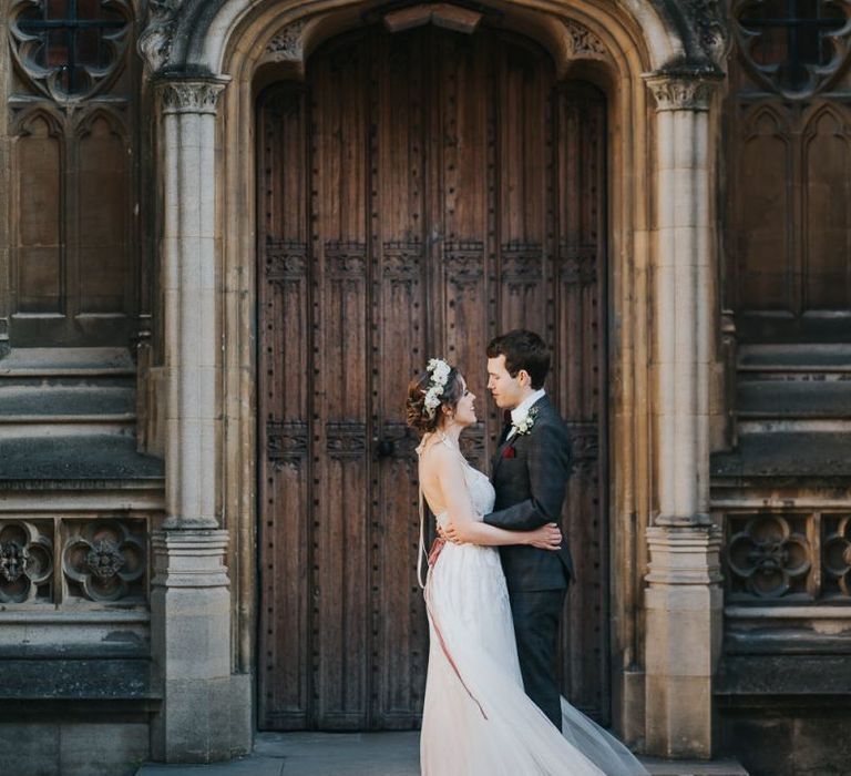 Bride and groom embrace at intimate celebration with floral head crown and lace detailed dress