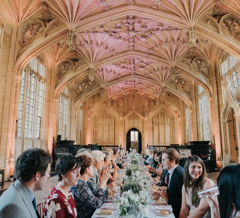 Guests enjoying an intimate and relaxed reception at Bodleian library with white floral centrepieces