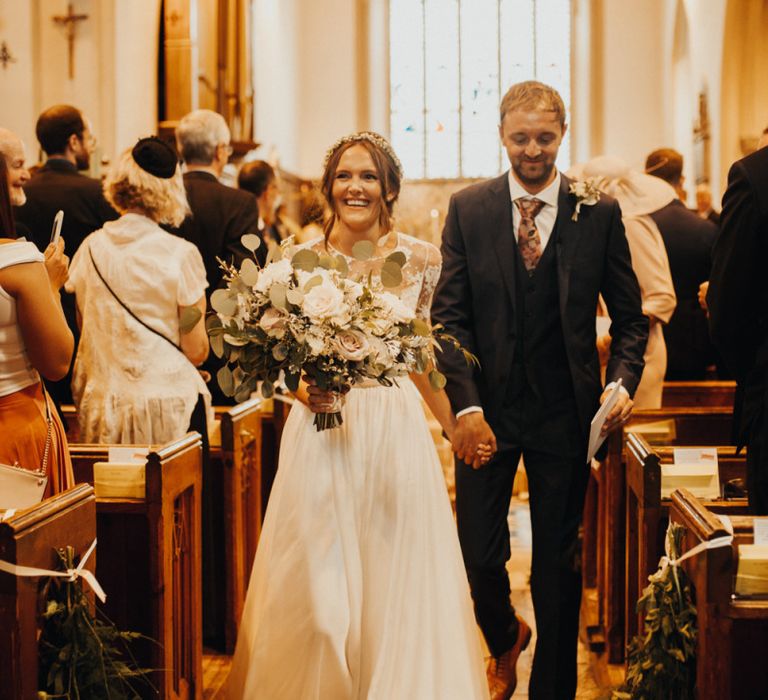 Bride and groom walk back up aisle after church ceremony