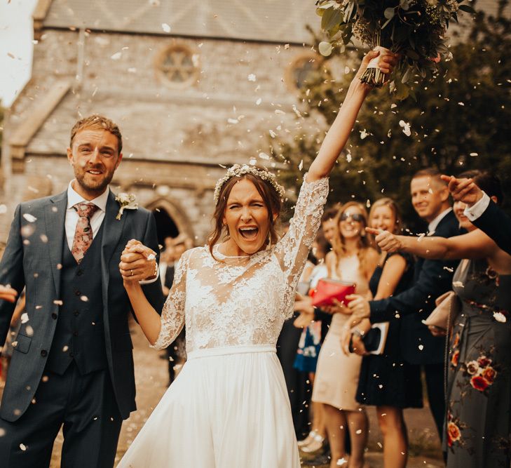 Confetti exit for bride and groom at wedding with floral chandelier and foliage table runner