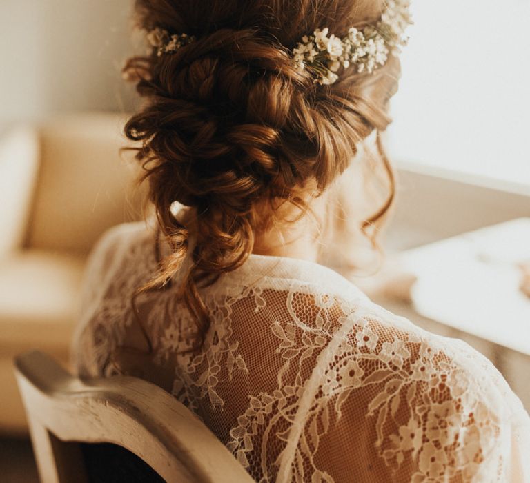 Bridal up do with flower crown at wedding with flower chandelier and foliage table runner