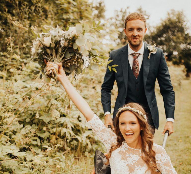 Groom pushes bride in wheelbarrow at Devonshire wedding