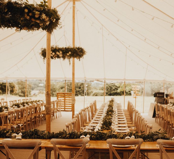 Marquee wedding decor with foliage table runner and floral chandelier