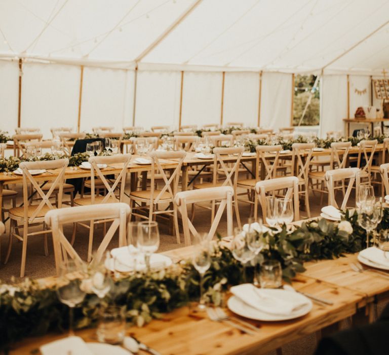 Marquee wedding decor with floral chandelier and foliage table plan