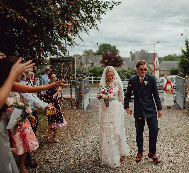 Confetti Moment | Bride in Laced Catherine Deane Wedding Dress with Long Sleeves | Groom in Blue Thomas Farthing Suit with Ochre Tie | Rustic French Destination Wedding with Homegrown Flowers  | Emily &amp; Steve Photography