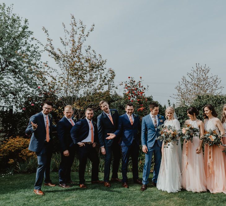 Wedding Party Portrait with Bridesmaids in Peach and White Separates, Bride in Lace Wedding Dress and Groom in Navy Blue Suits