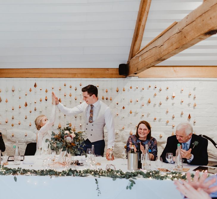 Bride and Groom Having a High Five at the Top Table with Geometric Backdrop