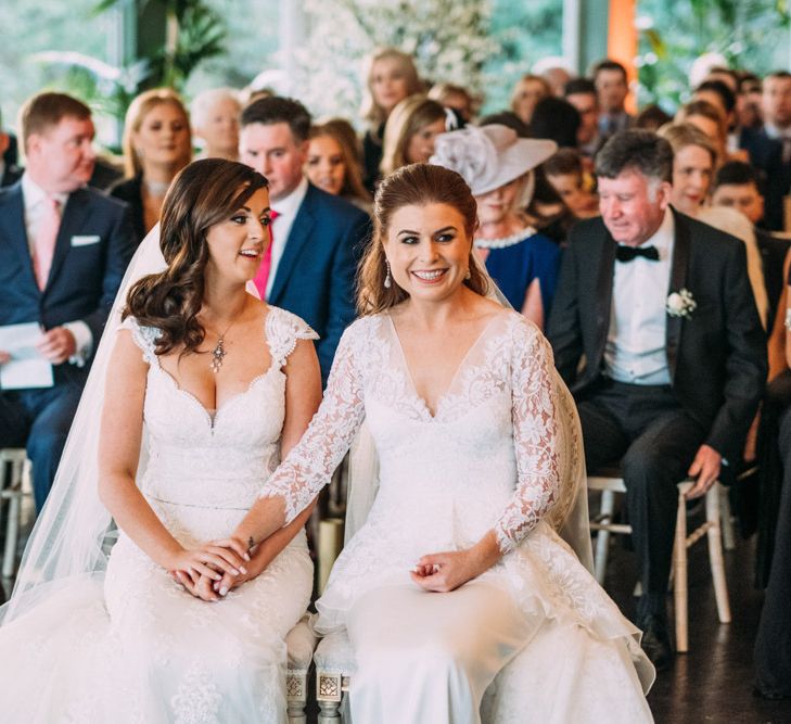 Two Brides in Lace Wedding Dresses Holding Hands at Wedding Ceremony