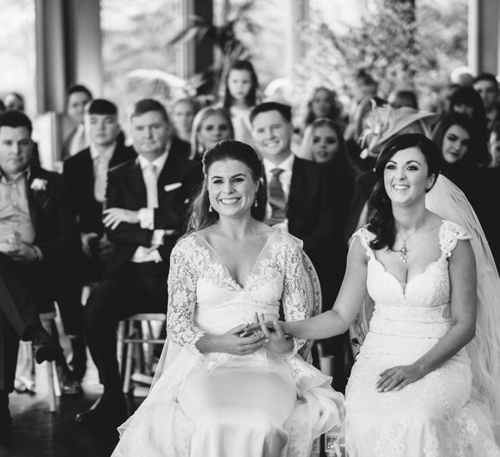 Two Brides in Lace Wedding Dresses Holding Hands at Wedding Ceremony