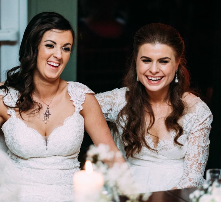 Two Bride in Lace Wedding Dresses Laughing at Wedding Reception Speeches