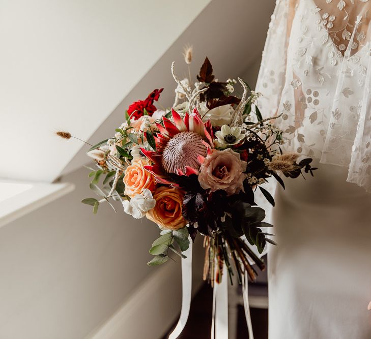 Bridal cape in lace over minimalist wedding dress with blush bouquet