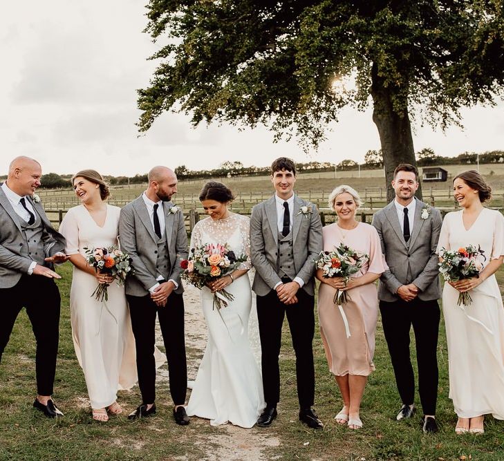 Bridal party in pink dresses with groomsmen in grey suits