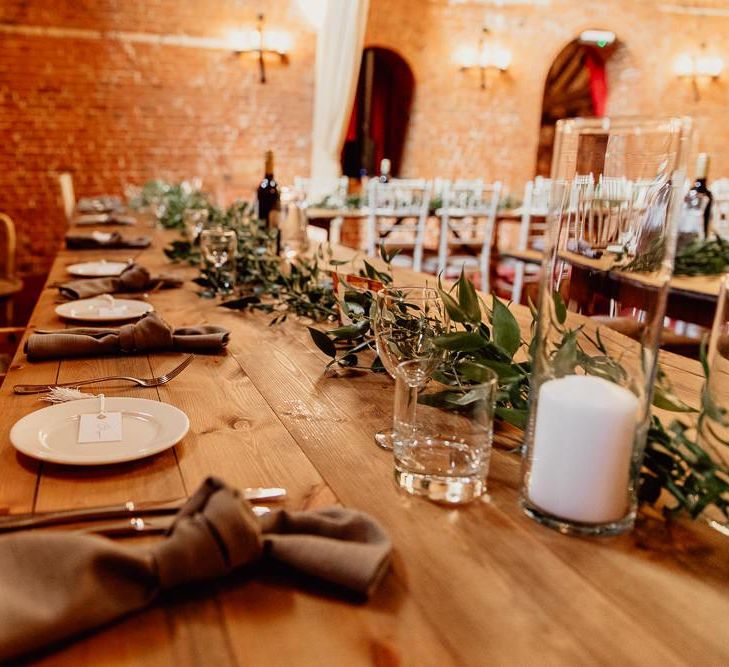 Foliage and candles on trestle tables at Norfolk barn wedding