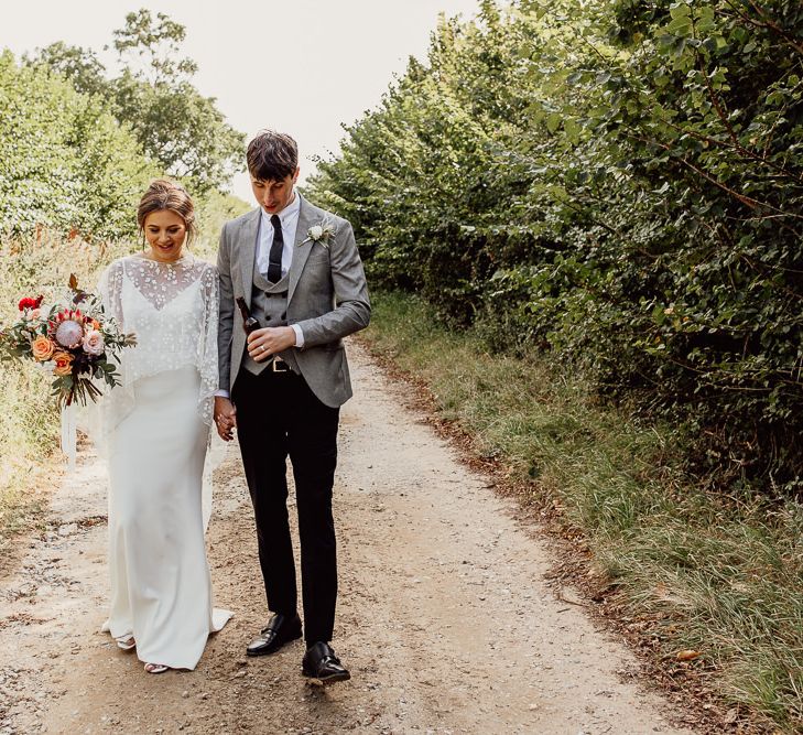 Bride and groom walk through grounds of Norfolk barn wedding venue