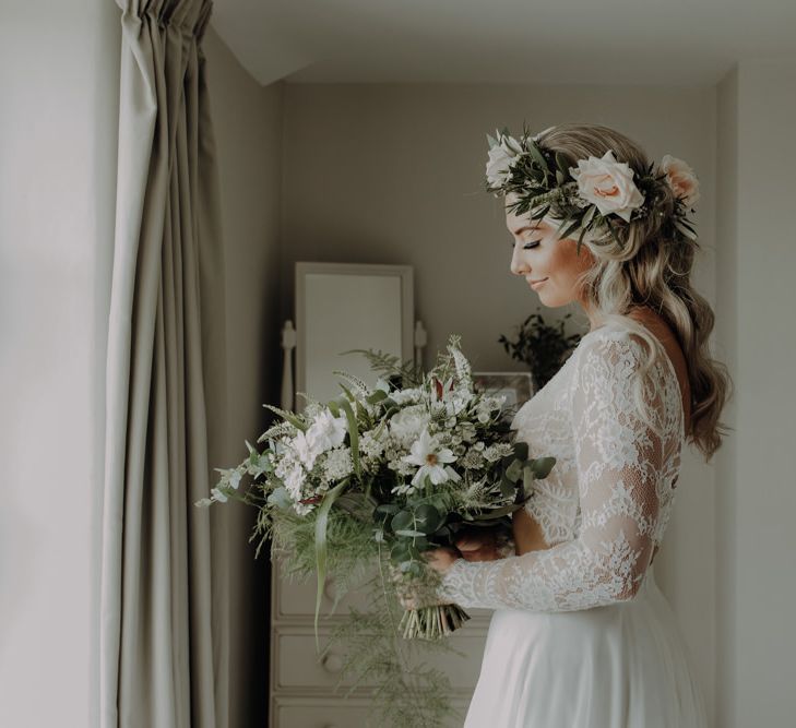 Bride wearing flower headpiece and holding white floral bouquet