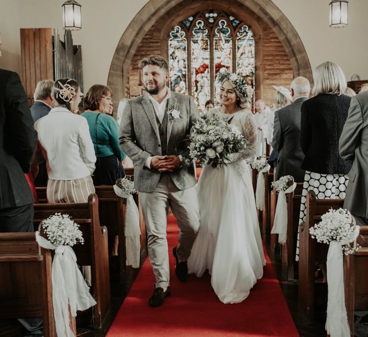 Bride and groom tie the knot at church ceremony wearing two piece bridal dress and white floral bouquet