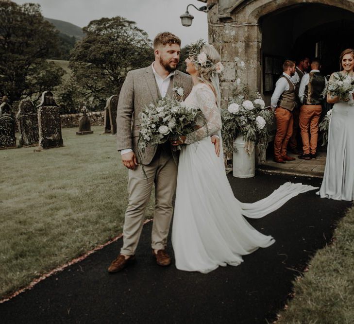 Bride and groom kiss at the church entrance with white floral decor