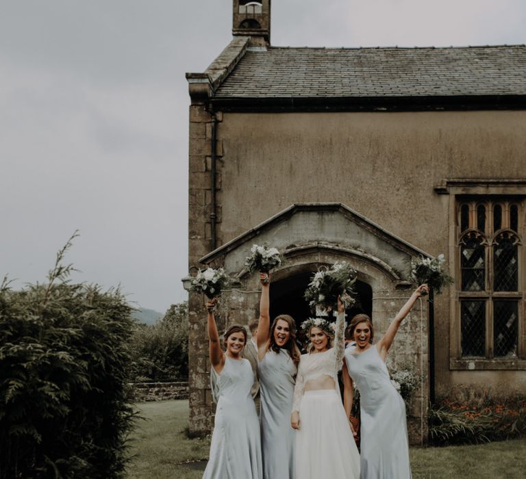 Bride and her bridesmaids with white floral bouquets at church ceremony