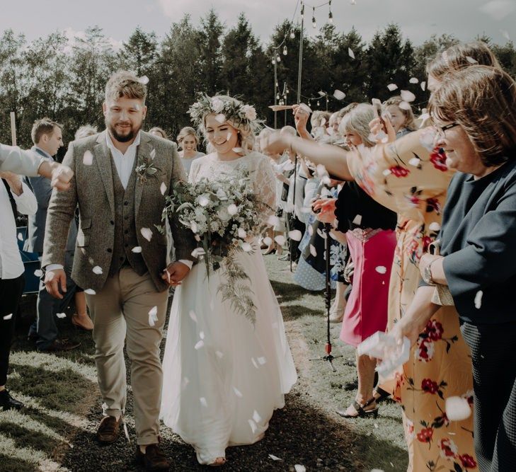 Bride and groom confetti shot wearing white flower crown at Hobbit Hill