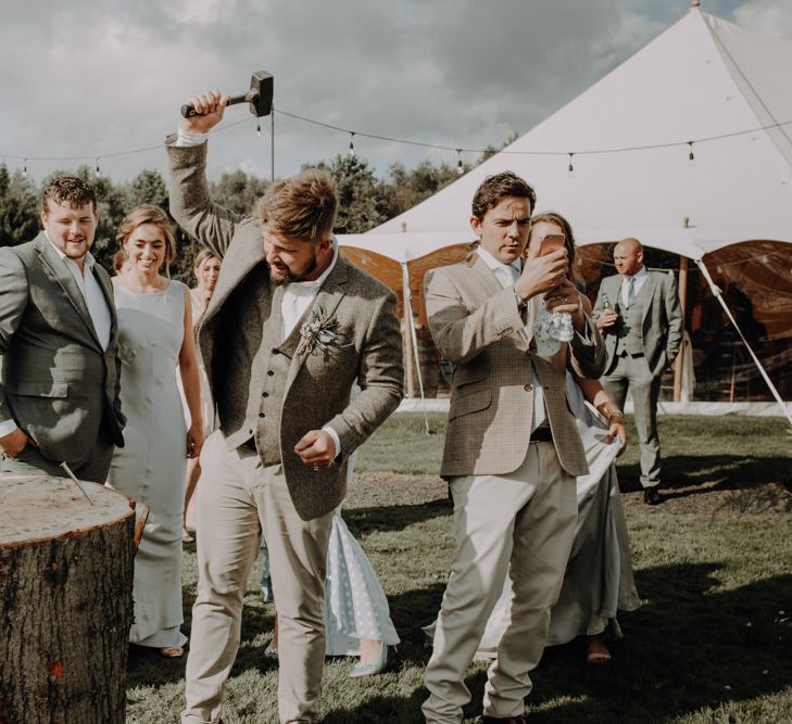 Groom playing hammershlagen at relaxed  outdoor wedding with marquee reception